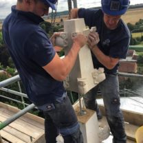 Image showing James one of the Company Directors and Anthony one of our Stonemasons lifting a new Pinnacle into place