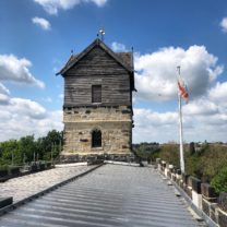 Image showing the Tower from the roof, showing the restore Weathervane, repaired timber panelling and the new and old Battlement Stones